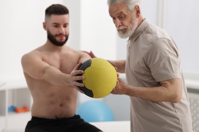 Photo of Doctor and patient exercising with medicine ball in clinic, selective focus