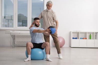 Photo of Doctor and patient exercising with medicine ball in clinic