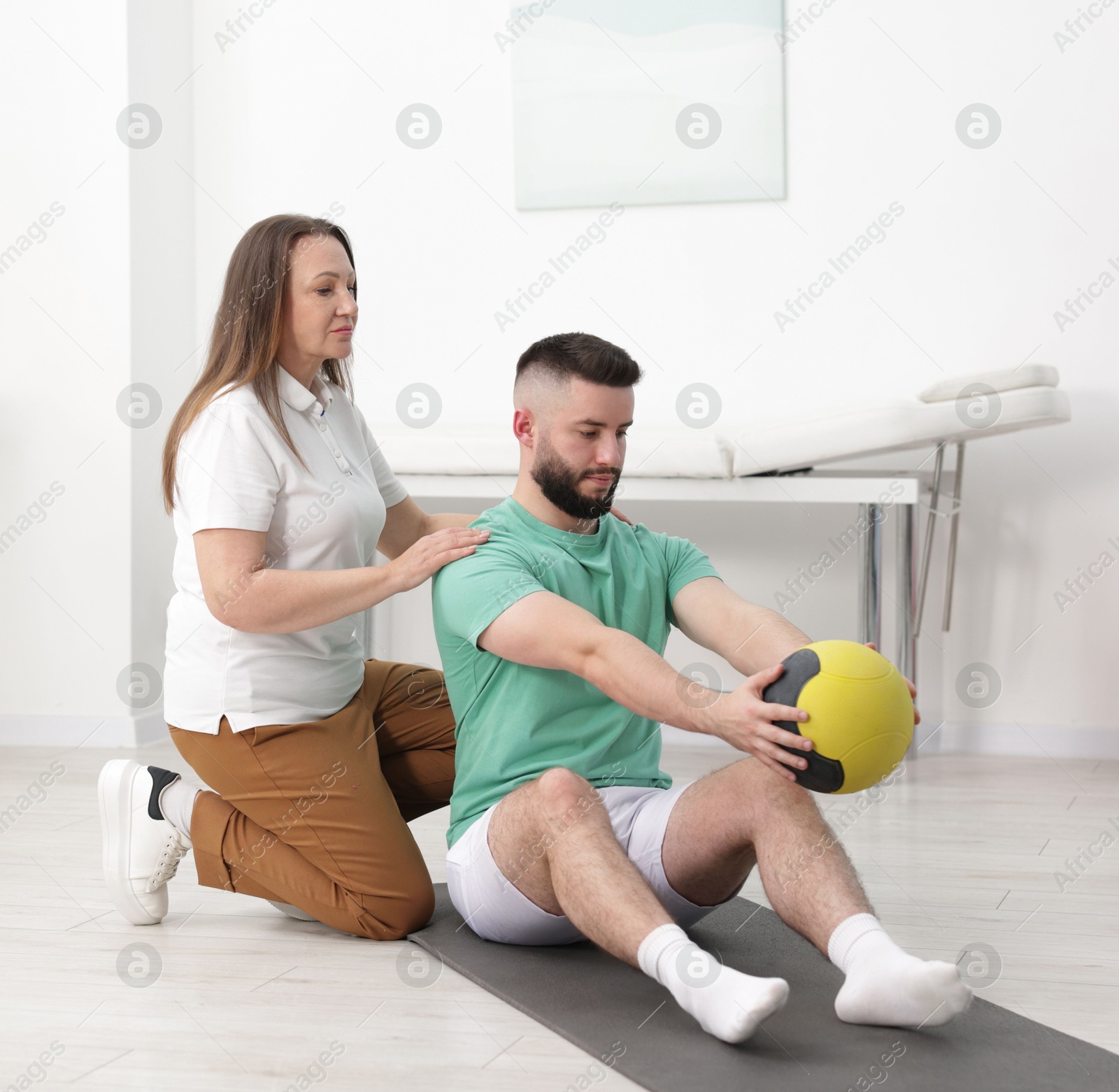 Photo of Doctor and patient exercising with medicine ball in clinic