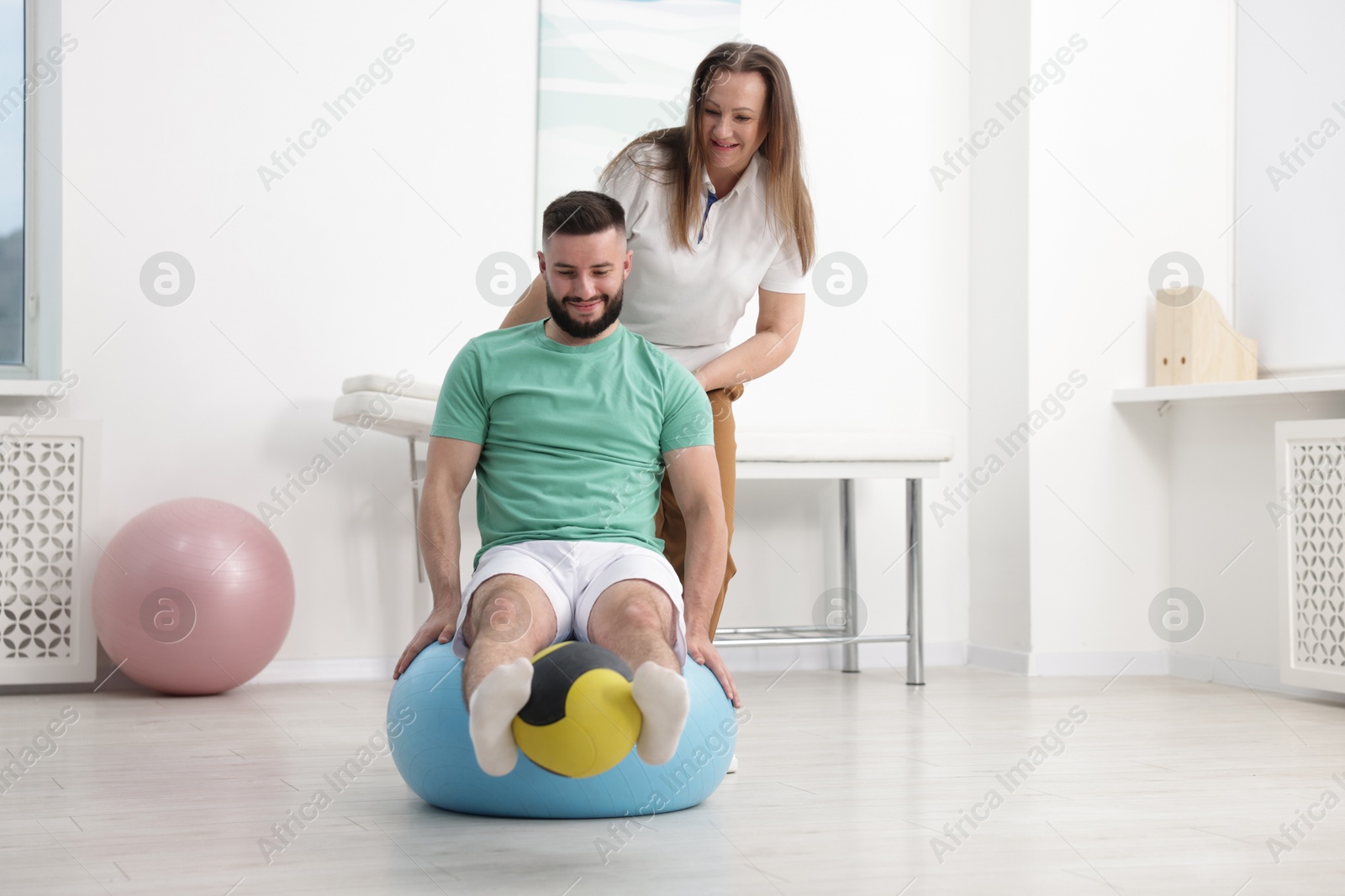 Doctor and patient exercising with medicine ball in clinic, space for text Photo of Doctor and patient exercising with medicine ball in clinic, space for text