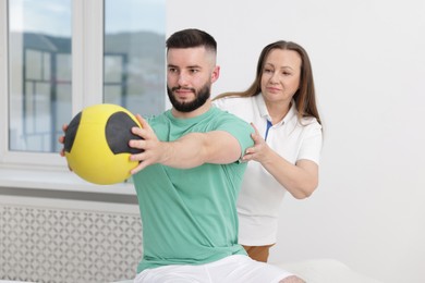 Photo of Doctor and patient exercising with medicine ball in clinic