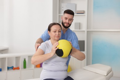 Photo of Doctor and patient exercising with medicine ball in clinic