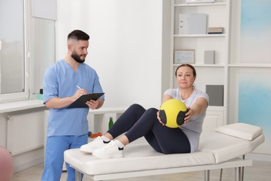 Photo of Doctor and patient exercising with medicine ball in clinic