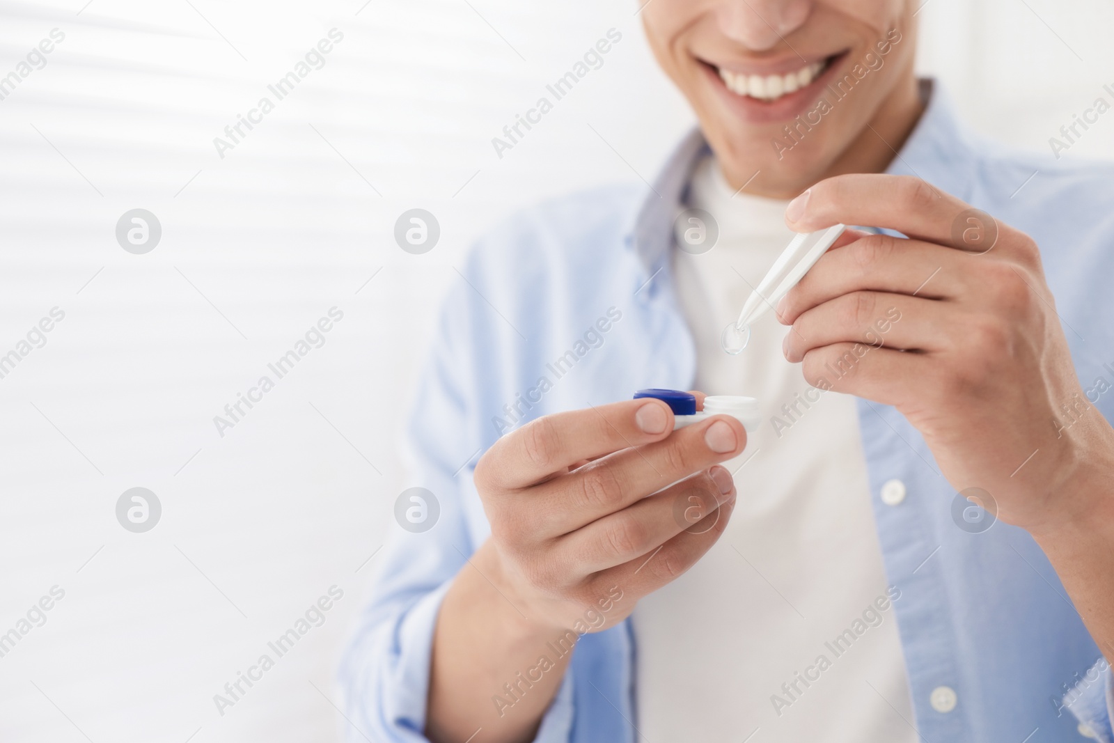 Man taking contact lens out of case at home, closeup. Space for text Photo of Man taking contact lens out of case at home, closeup. Space for text