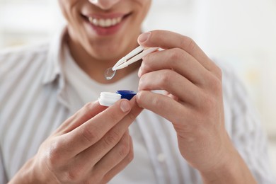 Photo of Man taking contact lens out of case at home, closeup