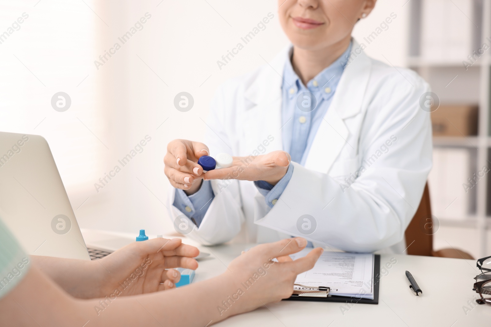 Ophthalmologist giving contact lenses to patient at table in office, closeup Photo of Ophthalmologist giving contact lenses to patient at table in office, closeup
