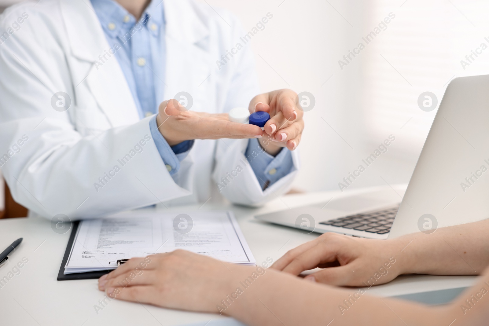 Ophthalmologist giving contact lenses to patient at table in office, closeup Photo of Ophthalmologist giving contact lenses to patient at table in office, closeup
