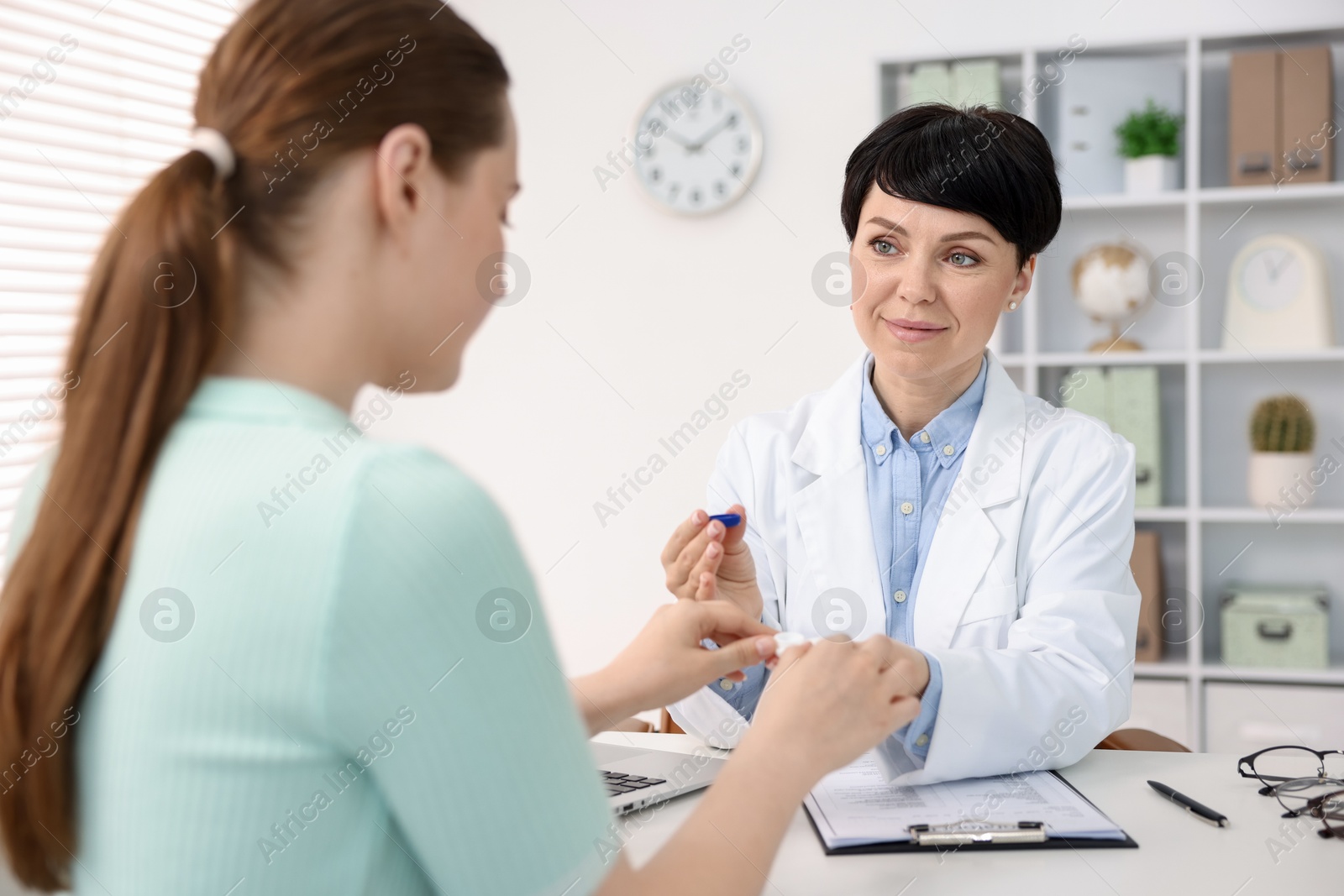 Ophthalmologist giving contact lenses to patient at table in office Photo of Ophthalmologist giving contact lenses to patient at table in office