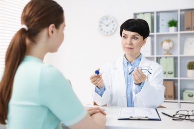 Photo of Ophthalmologist giving contact lenses and glasses to patient at table in office