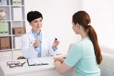 Photo of Ophthalmologist giving contact lenses and glasses to patient at table in office