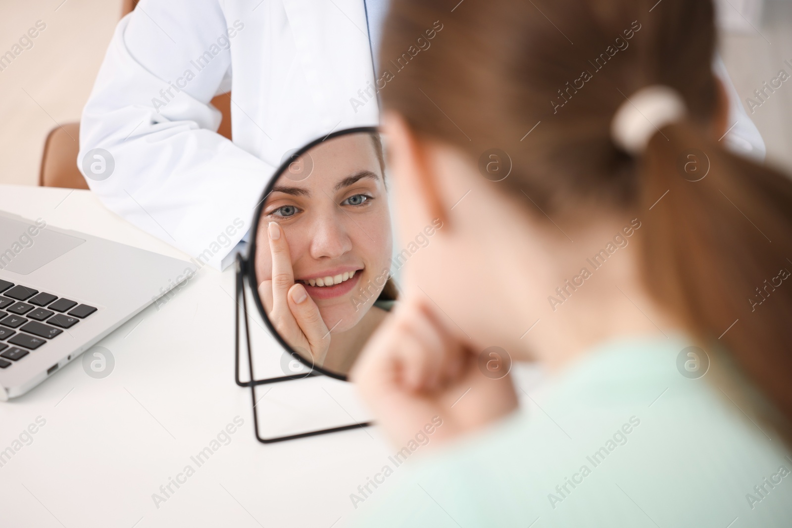Young woman putting on contact lenses at table near mirror in ophthalmologist office, selective focus Photo of Young woman putting on contact lenses at table near mirror in ophthalmologist office, selective focus