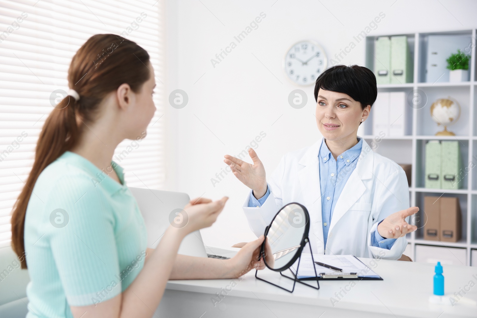 Ophthalmologist teaching patient to use contact lenses at table in office Photo of Ophthalmologist teaching patient to use contact lenses at table in office
