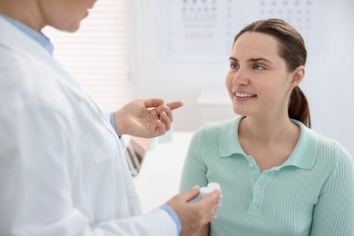 Photo of Ophthalmologist giving contact lenses to patient in office, closeup