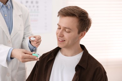 Photo of Ophthalmologist giving contact lenses to patient in office, closeup