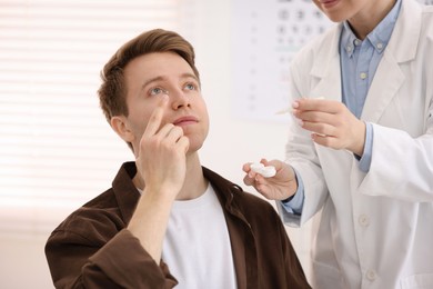 Photo of Young man putting on contact lenses in ophthalmologist office
