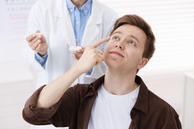 Photo of Young man putting on contact lenses in ophthalmologist office
