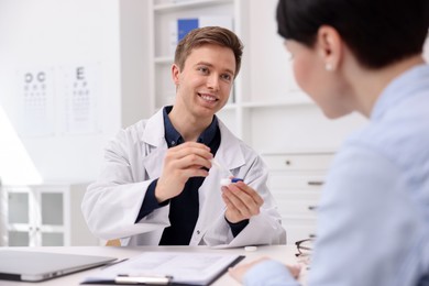 Photo of Ophthalmologist teaching patient to use contact lenses at table in office