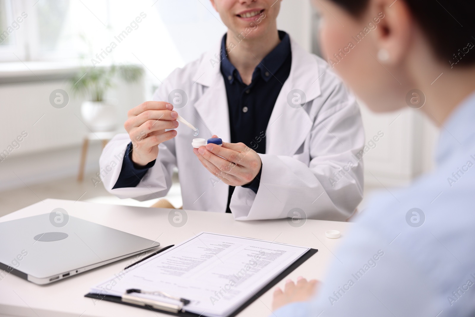Ophthalmologist teaching patient to use contact lenses at table in office, closeup Photo of Ophthalmologist teaching patient to use contact lenses at table in office, closeup