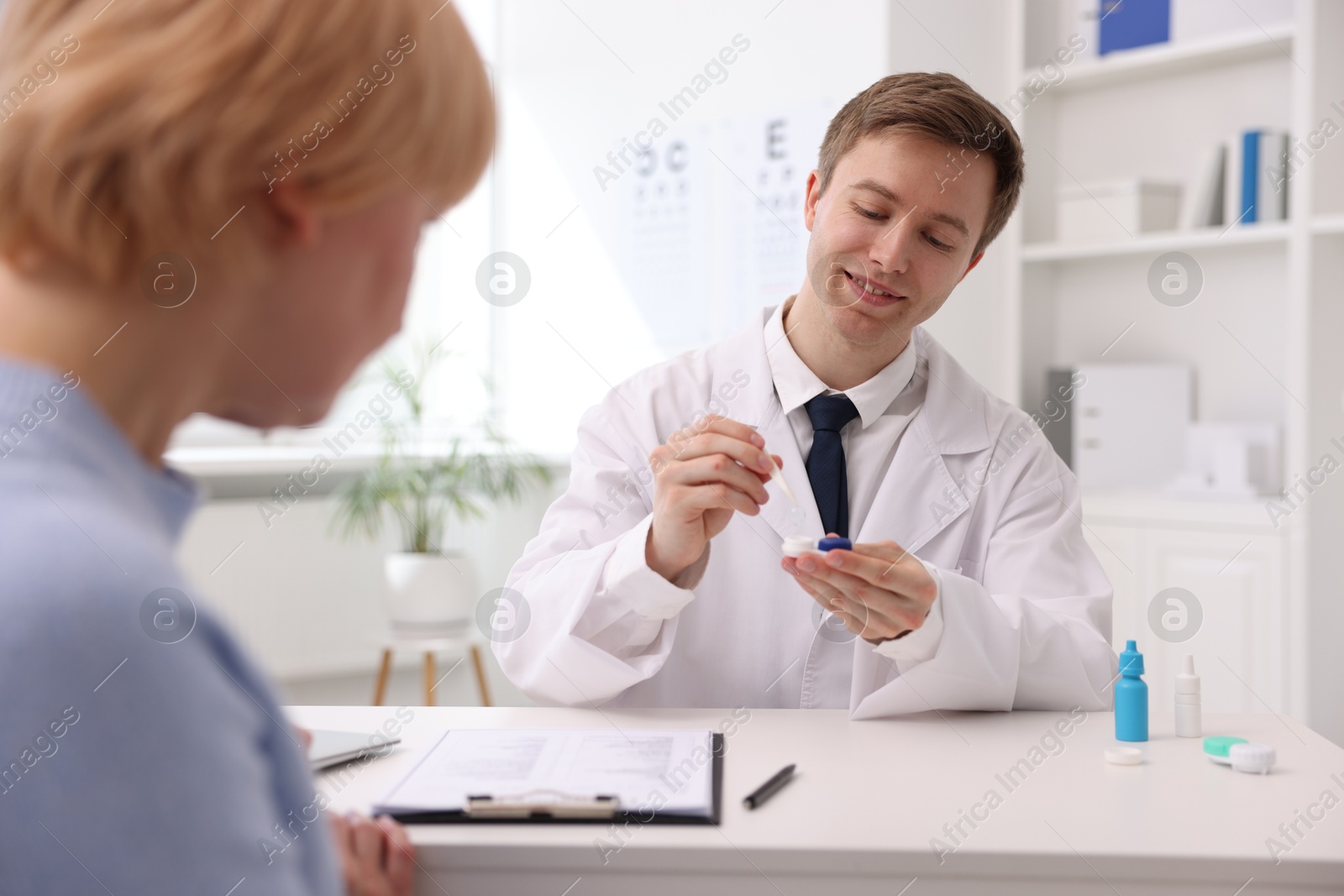Ophthalmologist teaching patient to use contact lenses at table in office Photo of Ophthalmologist teaching patient to use contact lenses at table in office