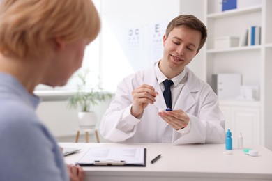 Photo of Ophthalmologist teaching patient to use contact lenses at table in office