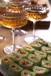 Photo of Buffet menu. Tasty rolls and sparkling wine on wooden table, closeup