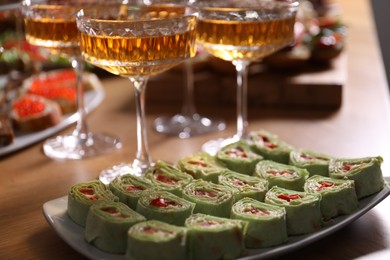 Photo of Buffet menu. Tasty rolls and sparkling wine on wooden table, closeup
