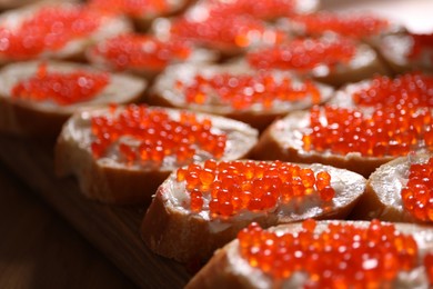 Photo of Buffet menu. Sandwiches with red caviar on wooden table, closeup