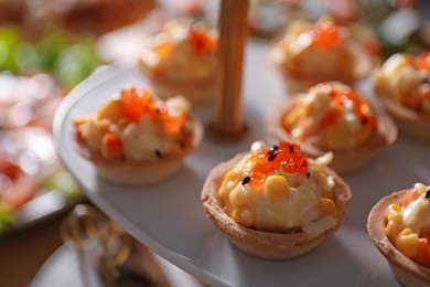 Photo of Buffet menu. Tasty stuffed tartlets on stand, closeup
