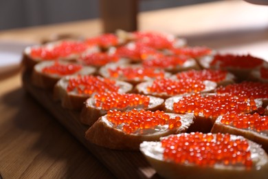 Photo of Buffet menu. Sandwiches with red caviar on wooden table, closeup
