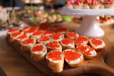 Photo of Buffet menu. Sandwiches with red caviar on wooden table, closeup