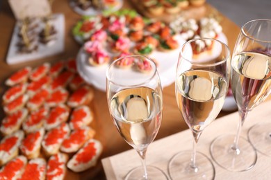 Photo of Buffet menu. Glasses of sparkling wine and tasty appetizers on table, closeup