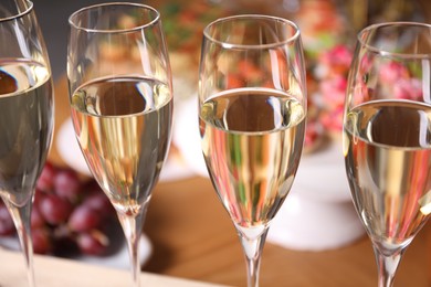Photo of Buffet menu. Glasses of sparkling wine and tasty appetizers on table, closeup