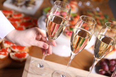 Photo of Buffet menu. Woman taking glass of sparkling wine from table, closeup