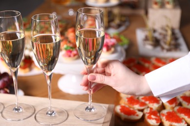 Photo of Buffet menu. Woman taking glass of sparkling wine from table, closeup