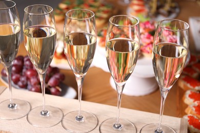 Photo of Buffet menu. Glasses of sparkling wine and tasty appetizers on table, closeup