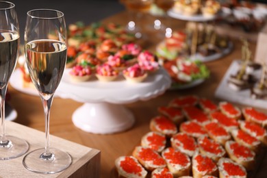 Photo of Buffet menu. Glasses of sparkling wine and tasty appetizers on table, closeup