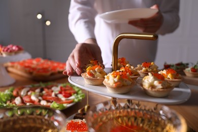 Photo of Buffet menu. Woman taking tasty tartlet from table, closeup