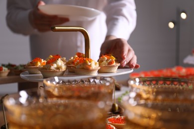 Photo of Buffet menu. Woman taking tasty tartlet from table, closeup