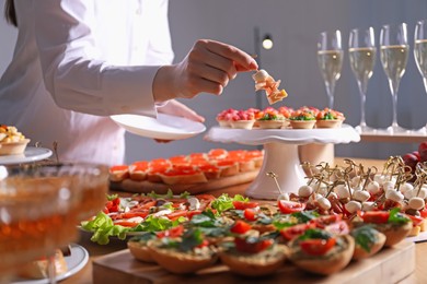 Photo of Buffet menu. Woman taking tasty canape from table, closeup