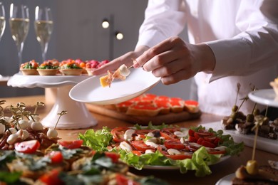 Photo of Buffet menu. Woman taking tasty canape from table, closeup