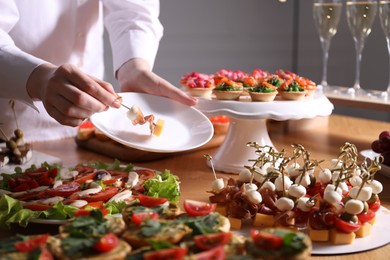 Photo of Buffet menu. Woman taking tasty canape from table, closeup