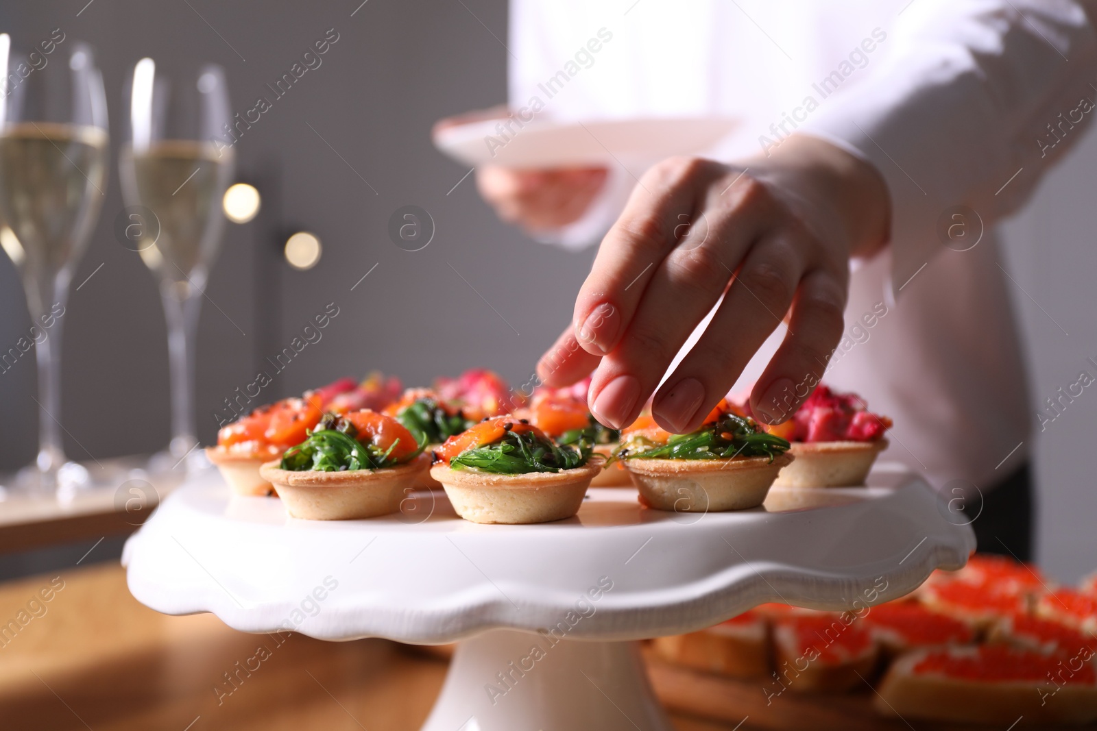 Buffet menu. Woman taking tasty tartlet from table, closeup Photo of Buffet menu. Woman taking tasty tartlet from table, closeup