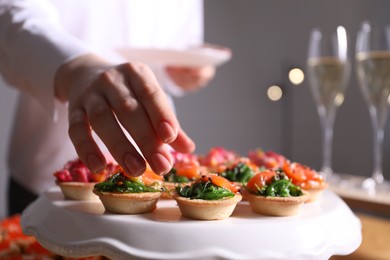 Photo of Buffet menu. Woman taking tasty tartlet from table, closeup