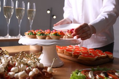 Photo of Buffet menu. Woman taking tasty tartlet from table, closeup