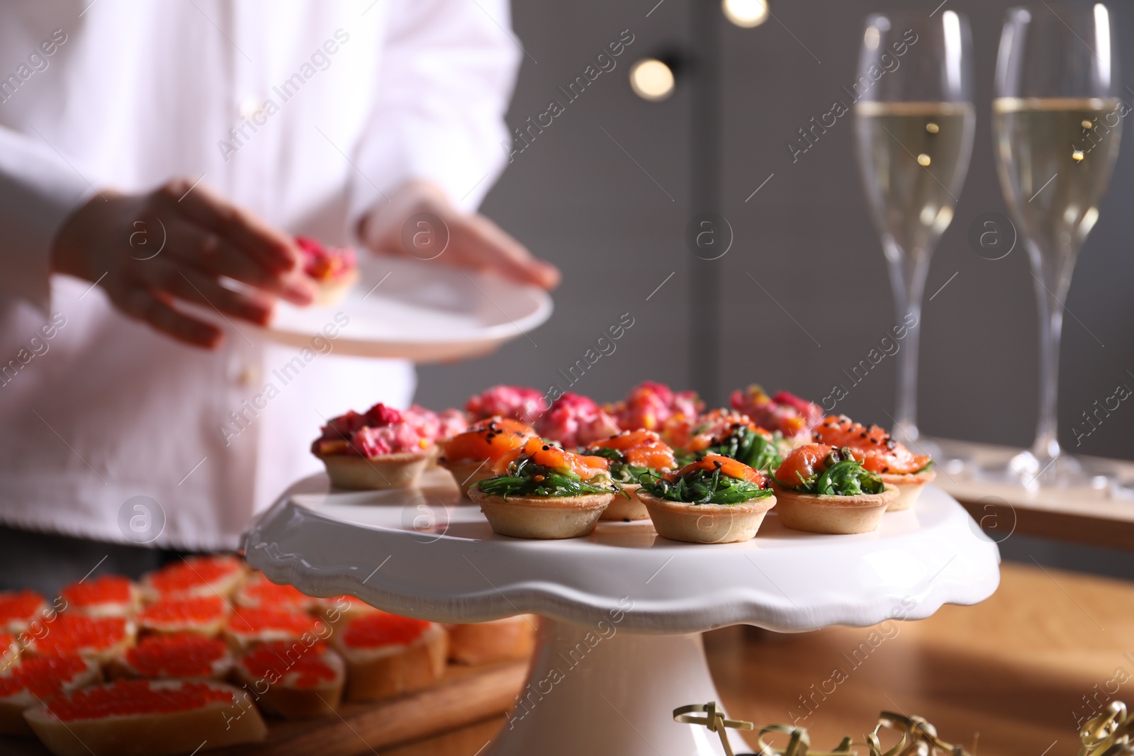 Buffet menu. Woman taking tasty tartlet from table, selective focus Photo of Buffet menu. Woman taking tasty tartlet from table, selective focus
