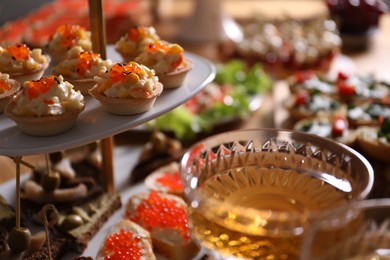 Photo of Buffet menu. Tasty stuffed tartlets and sparkling wine on table, closeup