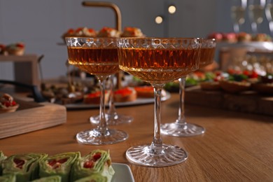 Photo of Buffet menu. Glasses of sparkling wine and tasty appetizers on table, closeup