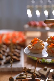 Photo of Buffet menu. Tasty stuffed tartlets on stand, closeup