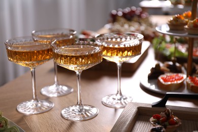 Photo of Buffet menu. Glasses of sparkling wine and tasty appetizers on table, closeup