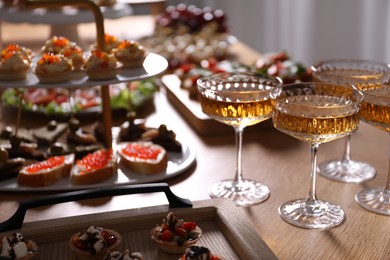 Photo of Buffet menu. Glasses of sparkling wine and tasty appetizers on table, closeup